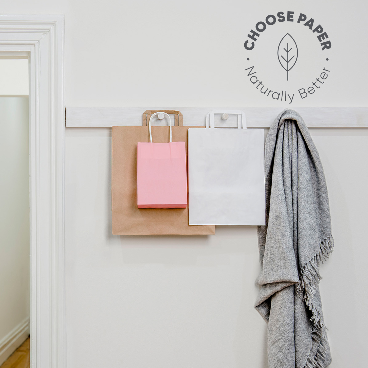 Kraft, white and pink paper bags hanging on wall hooks.