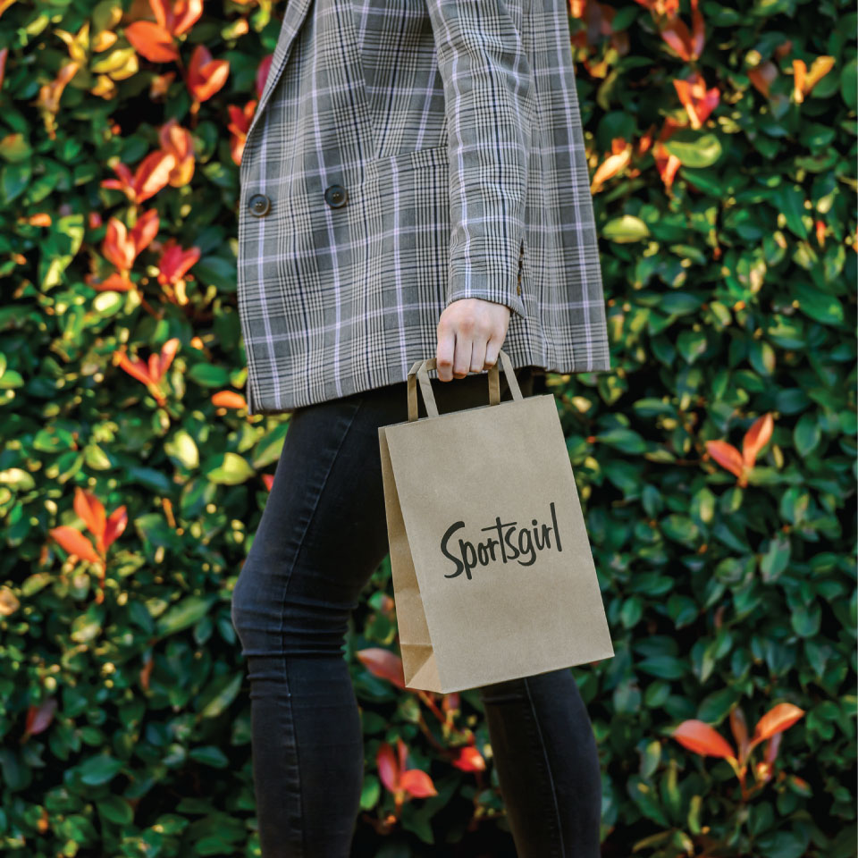 Woman walking with Sportsgirl paper bag.