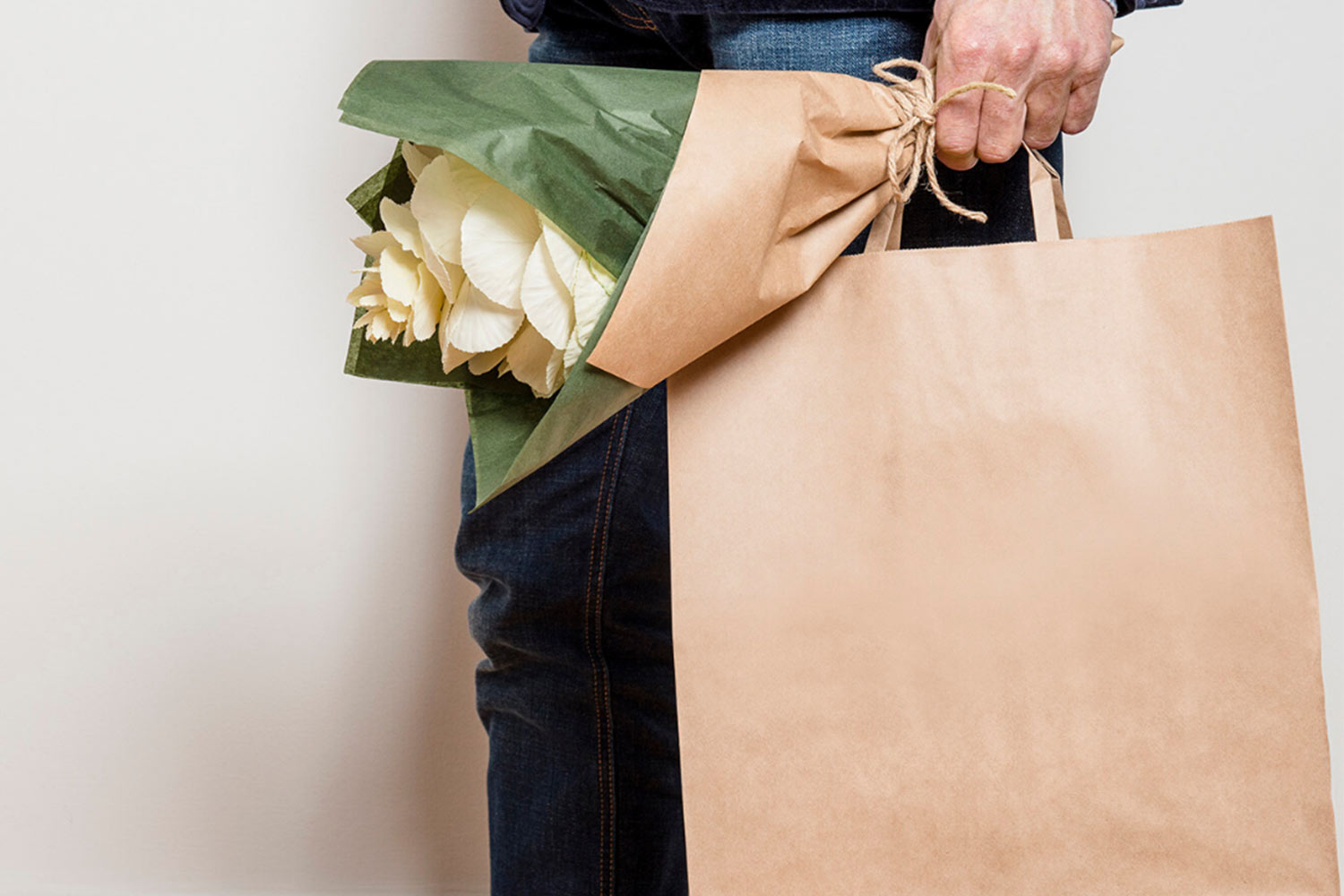 Man holding paperpak kraft bag with bouquet of flowers