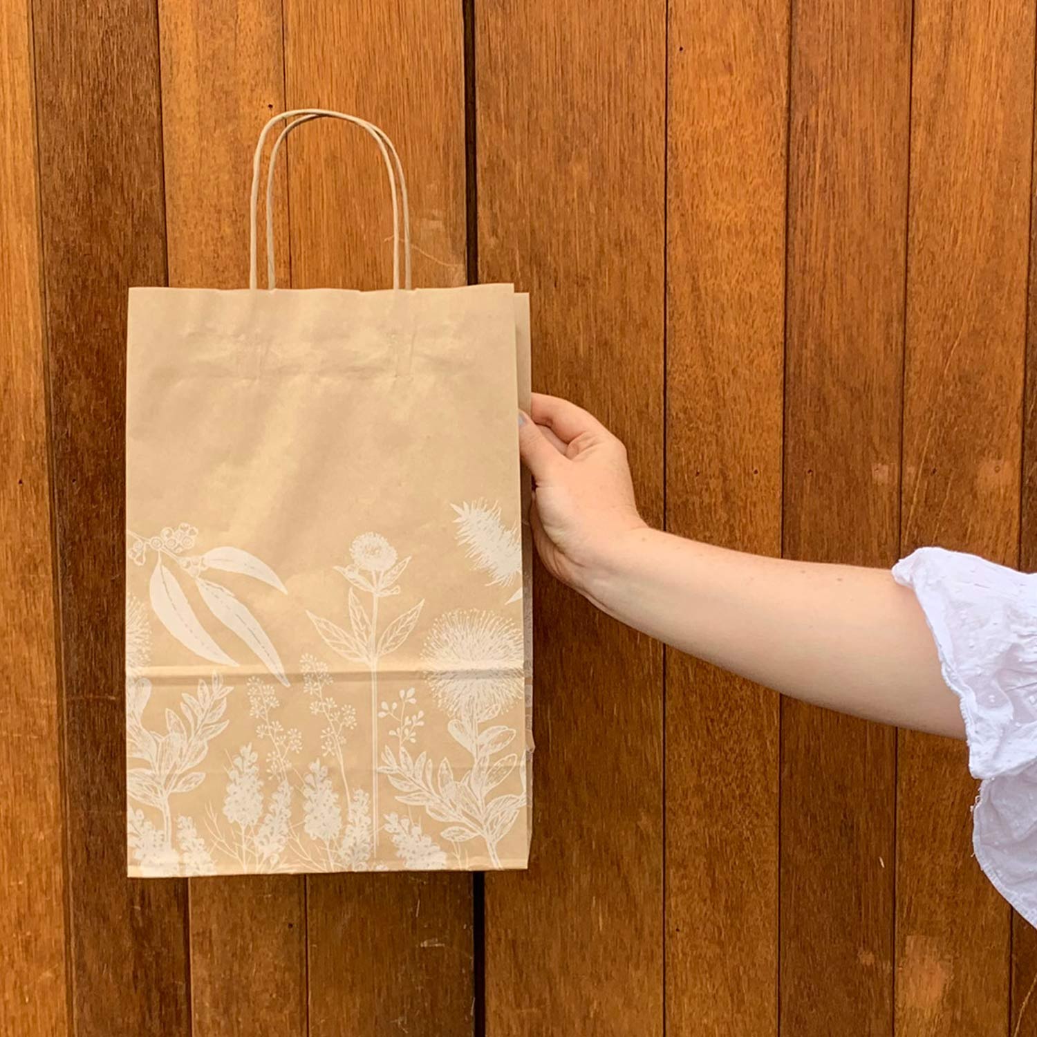 Image of Matilda Bag held in front of a timber wall